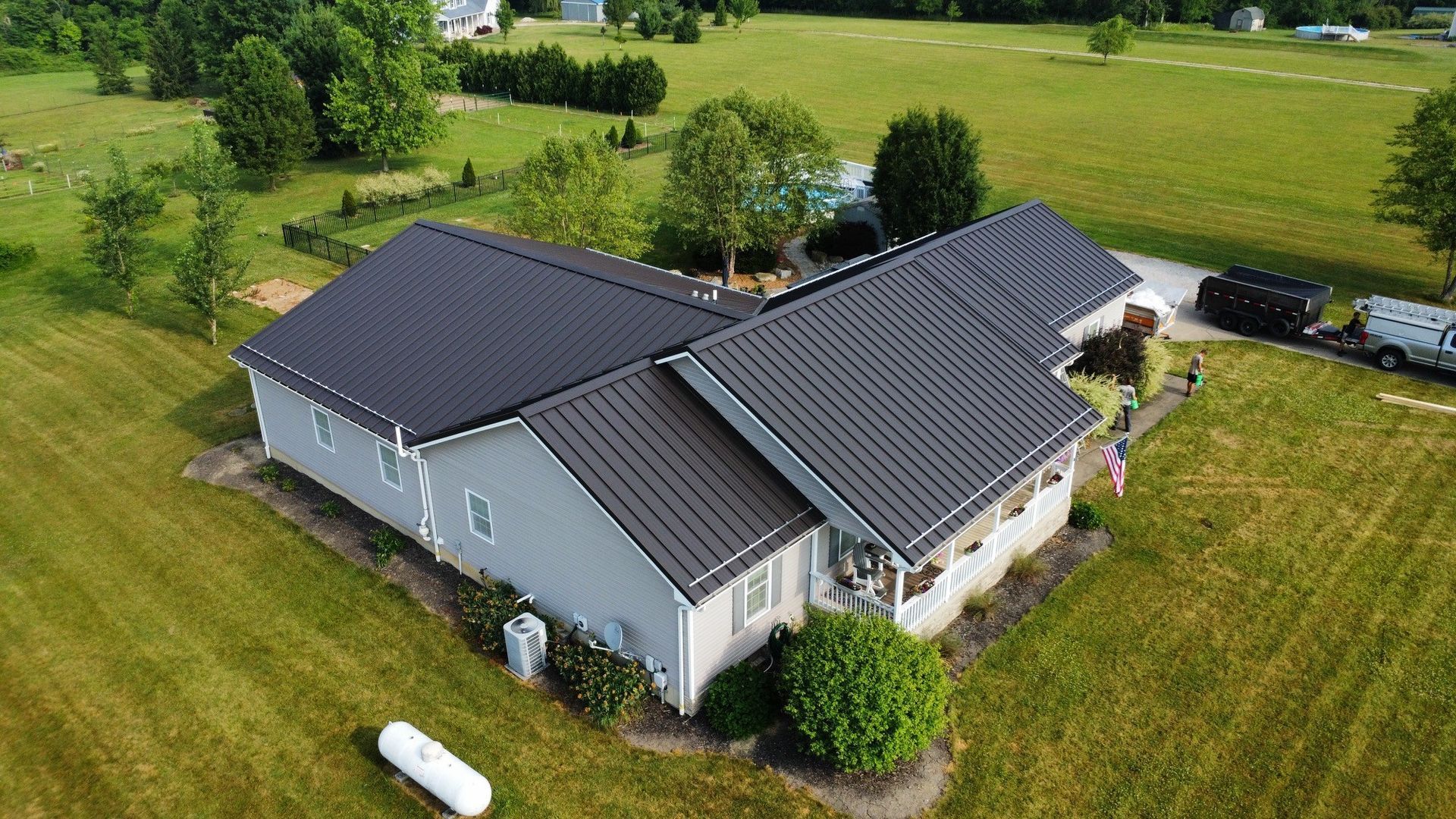 An aerial view of a house with a black roof in a grassy field.