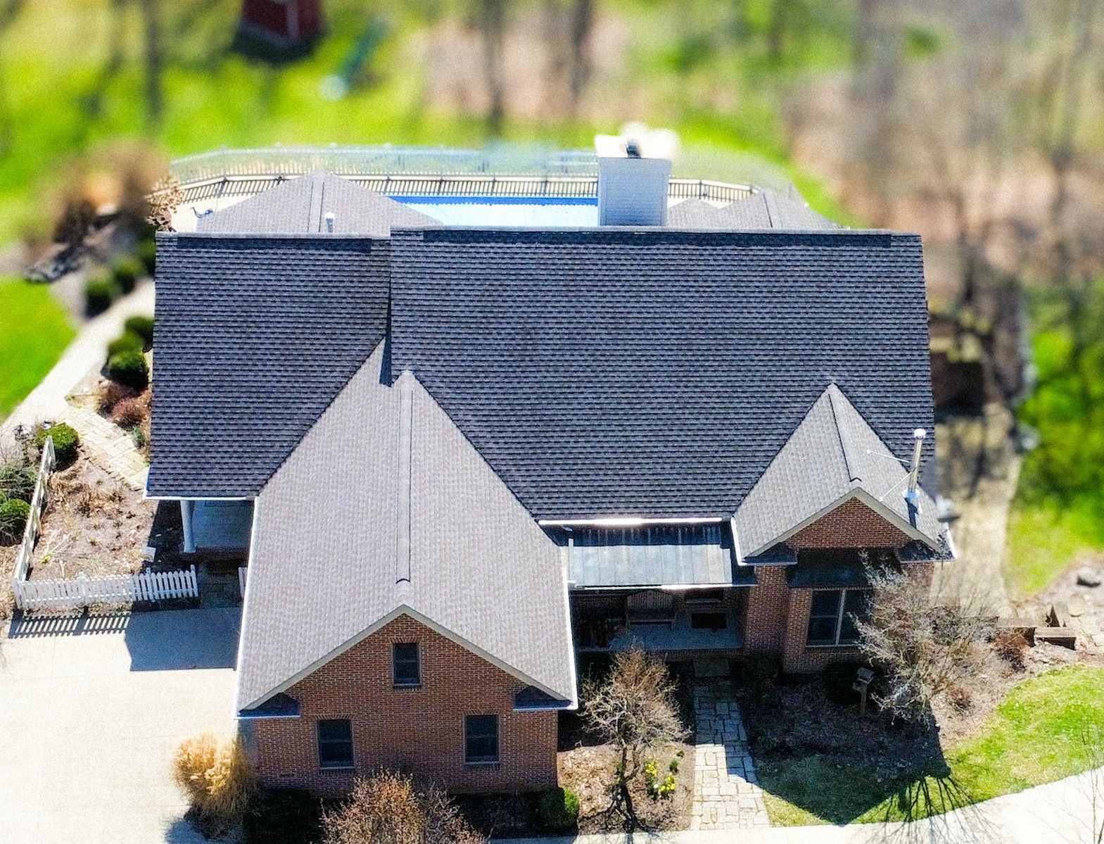 An aerial view of a large brick house with a gray roof.