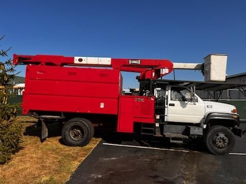 Red and white tree trimming truck with an elevated bucket.