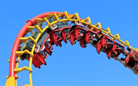 A roller coaster at an amusement park with a blue sky in the background.