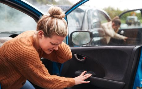 A woman is sitting in a car after a car accident.