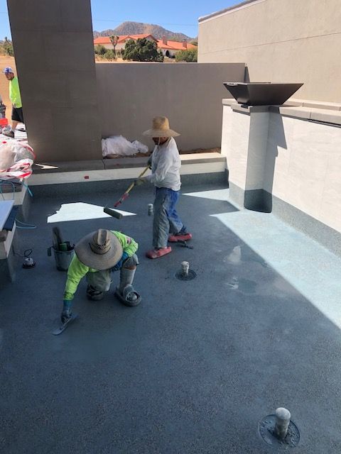 Children in hats kneeling and standing on a rooftop patio with small objects on the floor