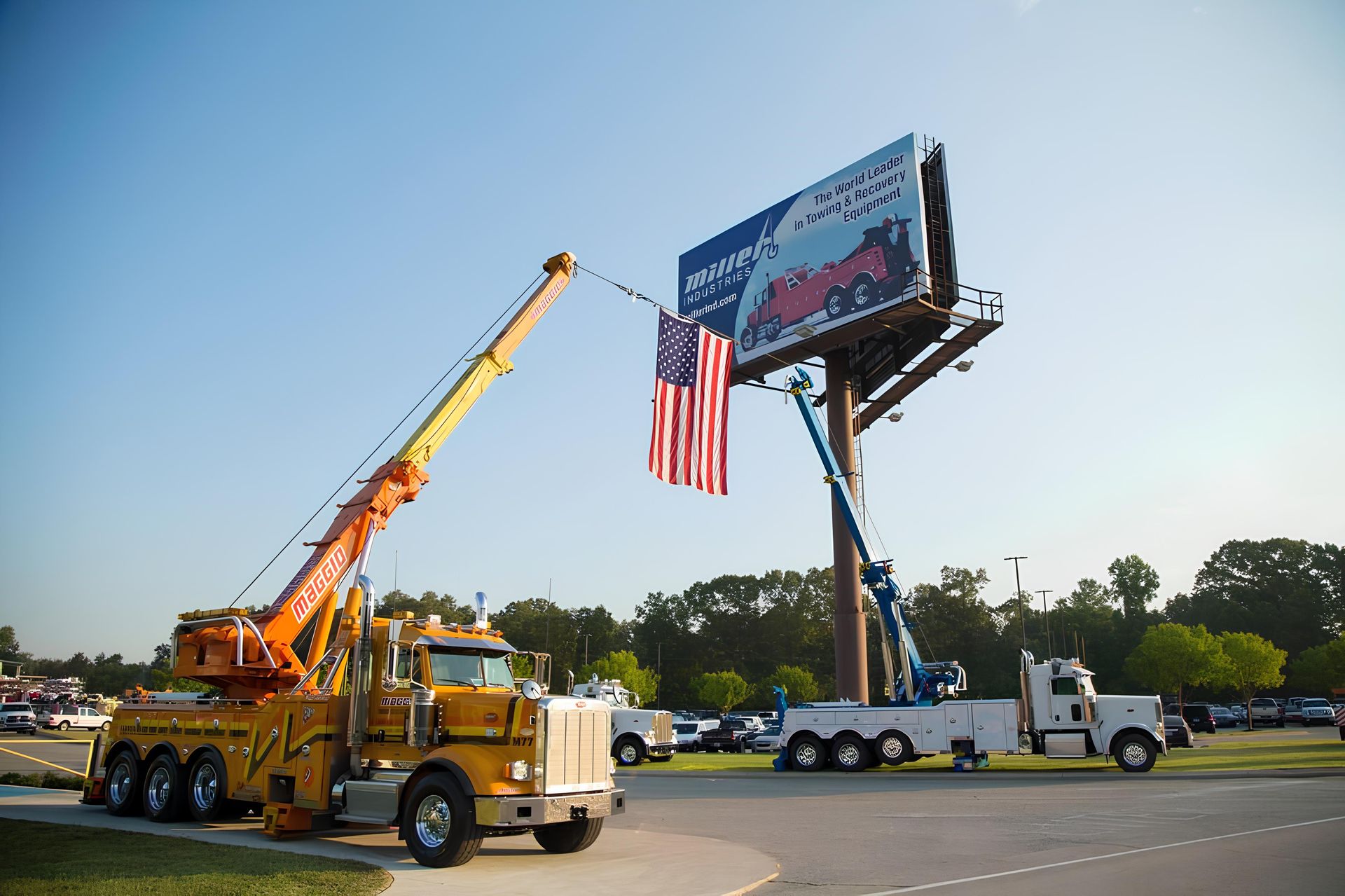 Tow trucks raising American flag on a billboard, outdoor sunny setting.