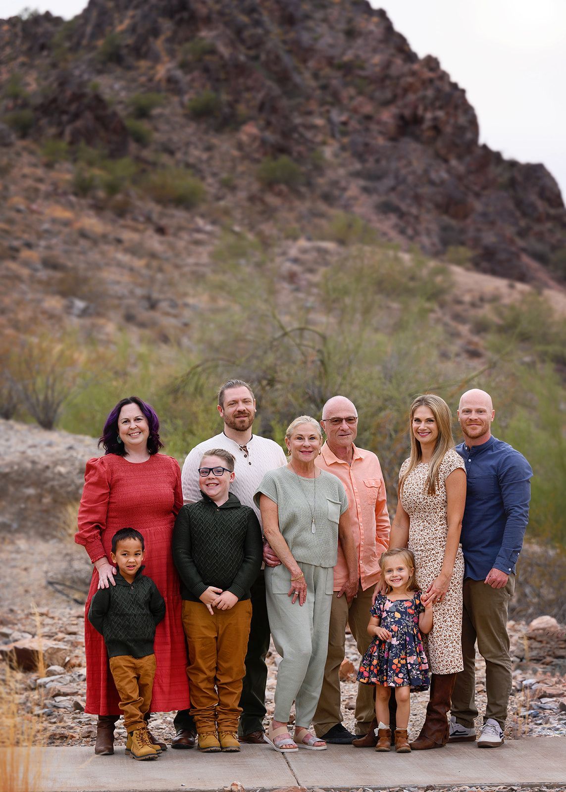 Group of people posing outdoors on a rocky path with mountains in the background.