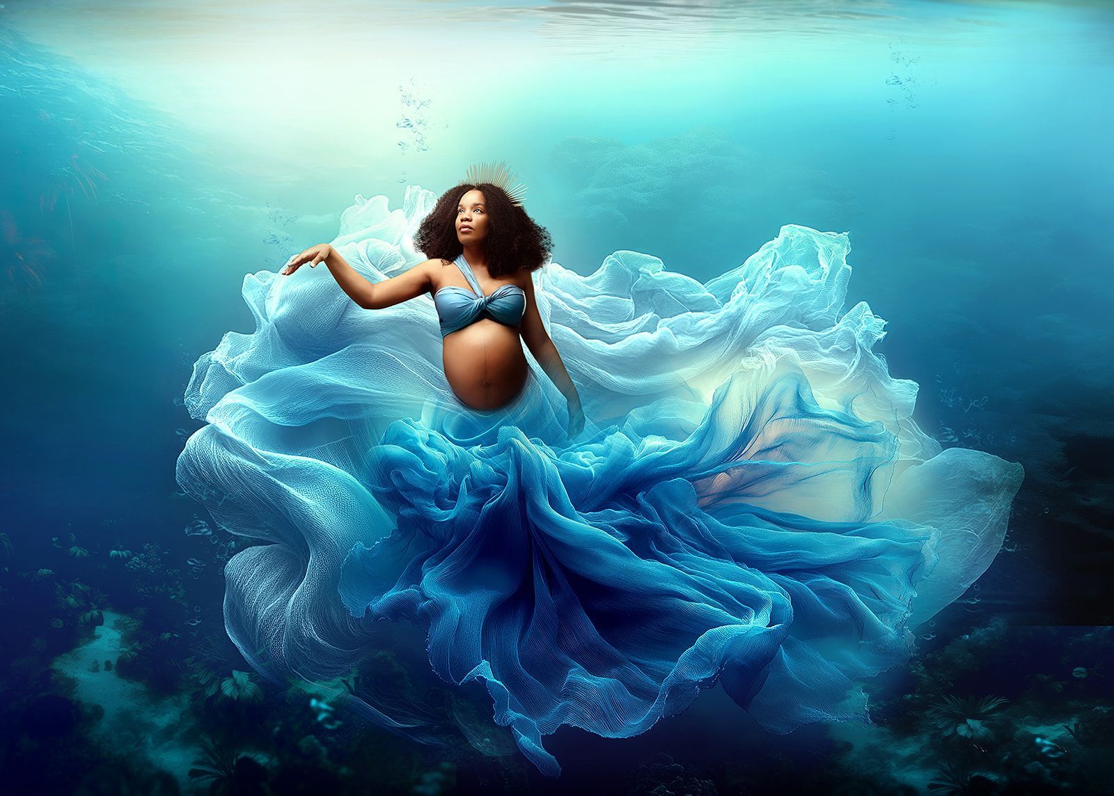 Pregnant woman in a flowing blue dress floating underwater in a dreamlike scene.