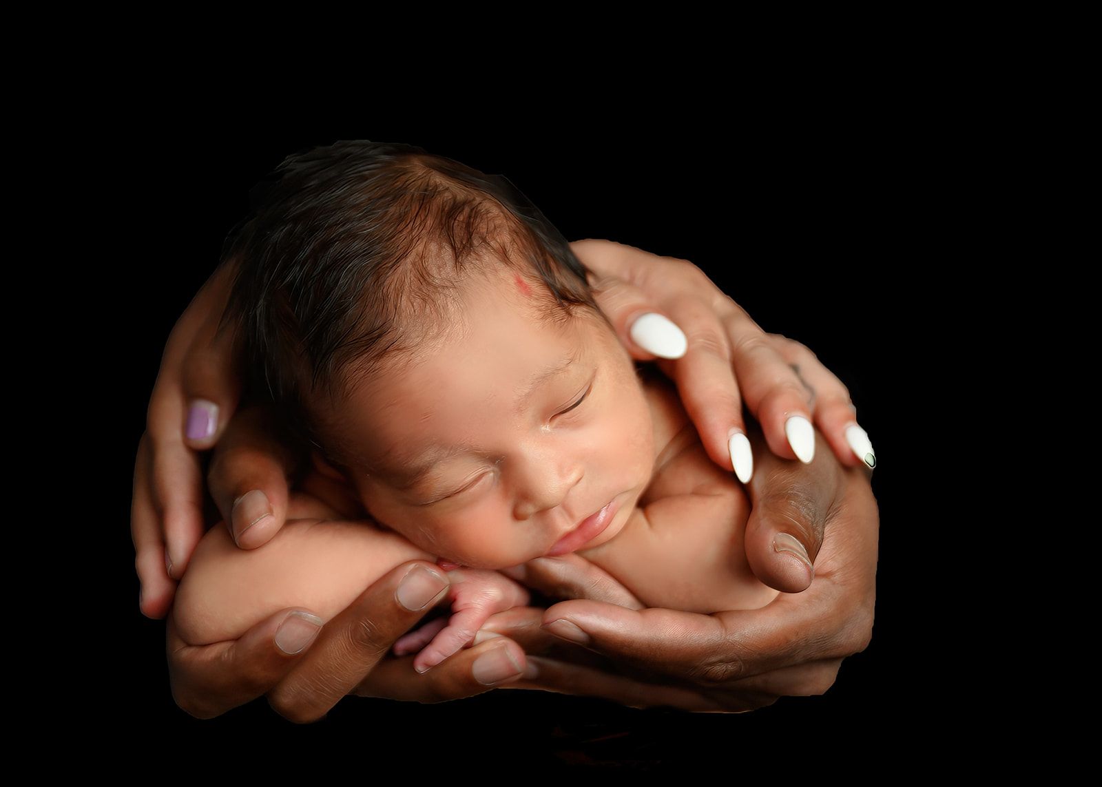 Sleeping newborn cradled in hands, softly lit against a black background.