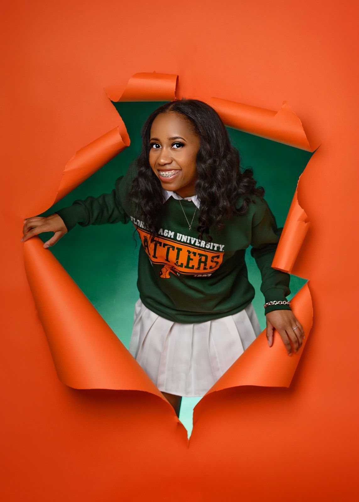 Woman in green and orange jacket emerging through torn orange paper background.