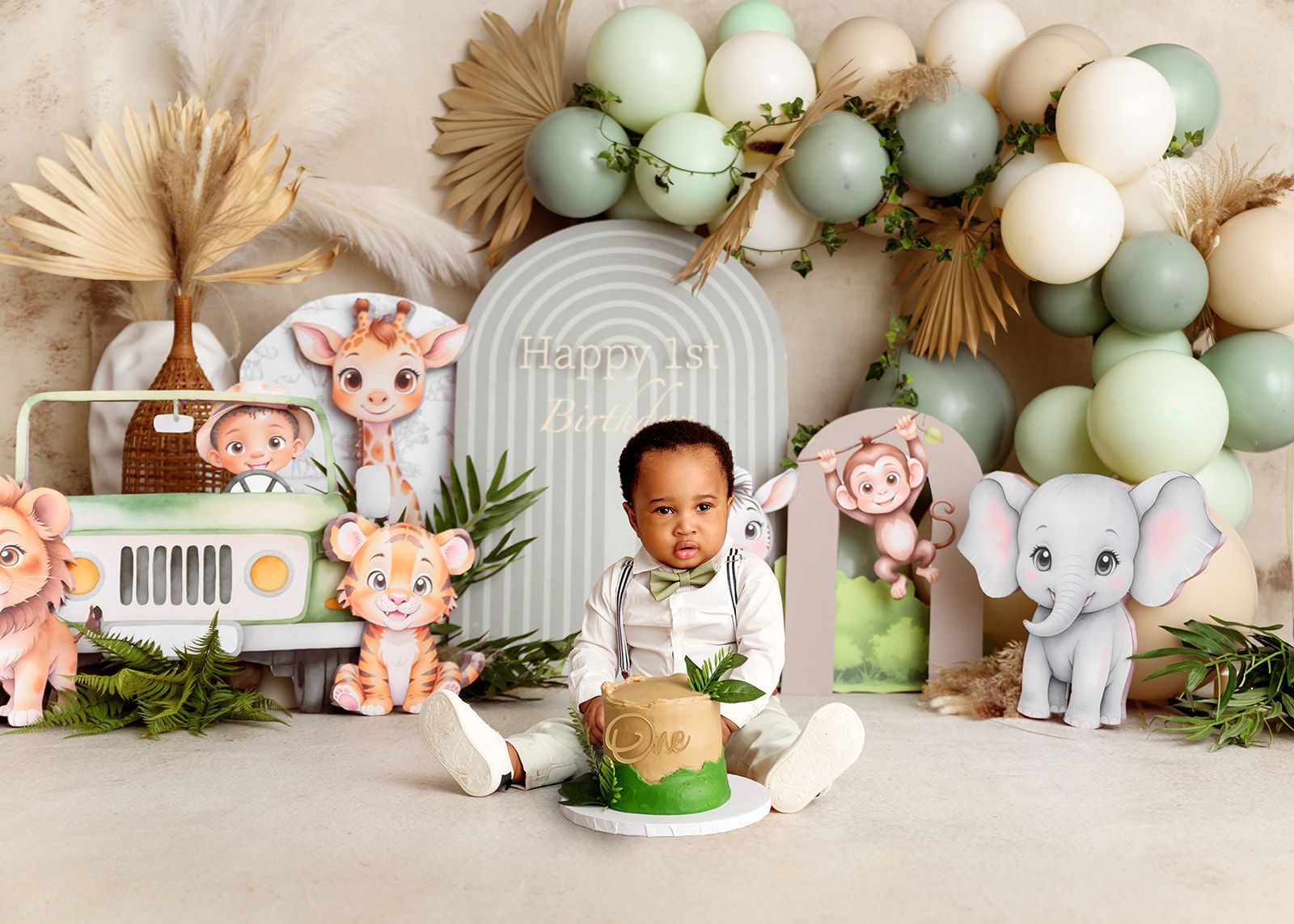 Baby seated in a forest-themed birthday setup with pastel balloon arch and animal decorations.