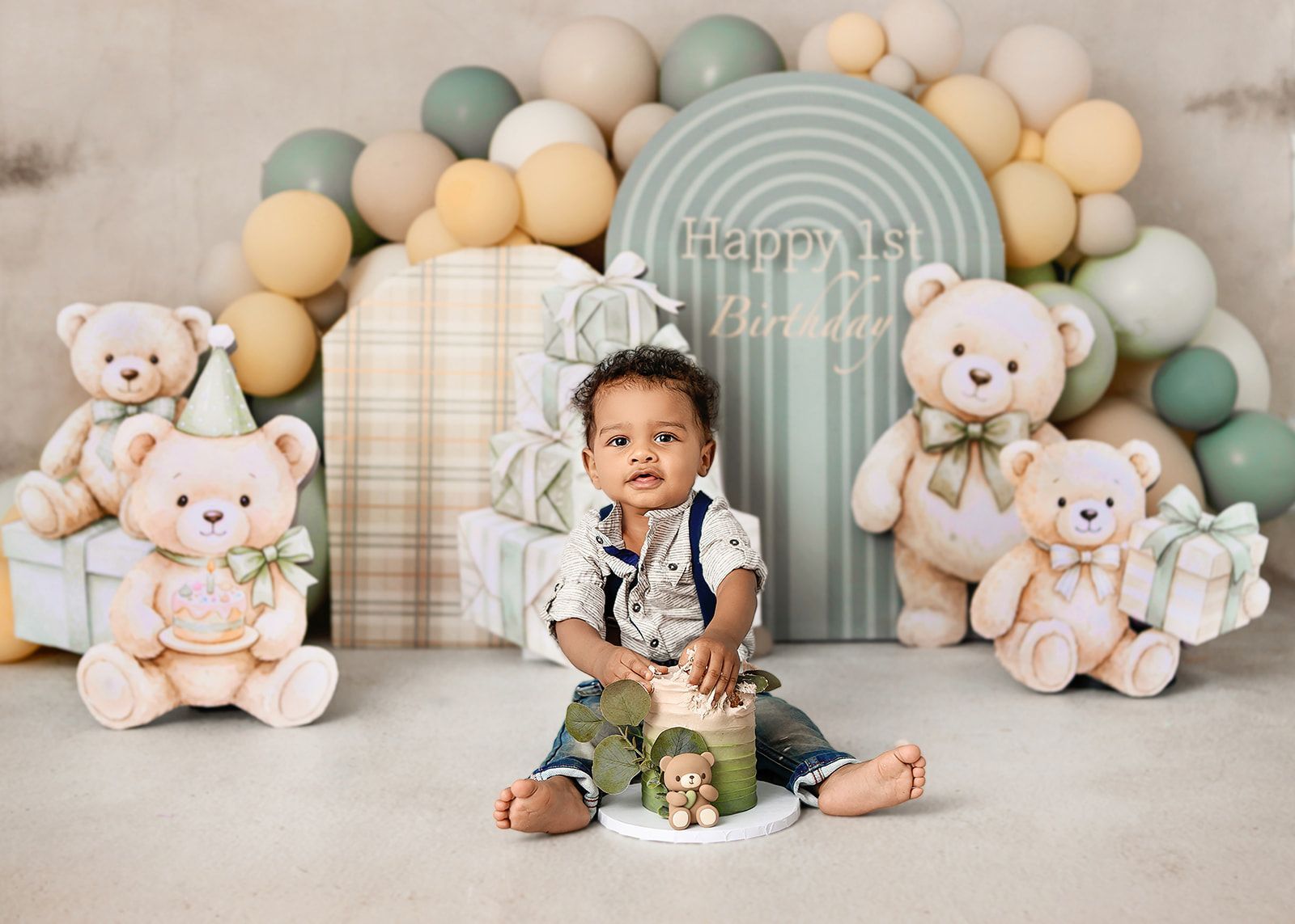 Baby sitting in a pastel balloon birthday setup with teddy bear decorations and gift boxes.