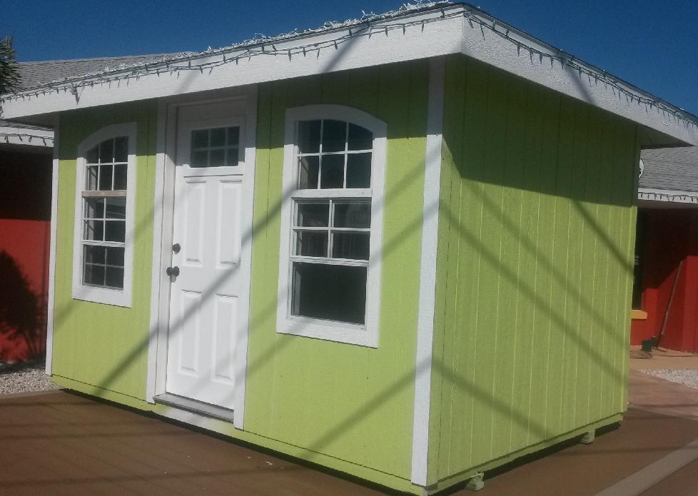 A green shed with white trim and windows