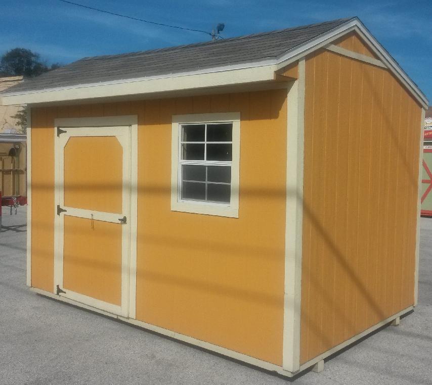 A yellow shed with a white trim and a window