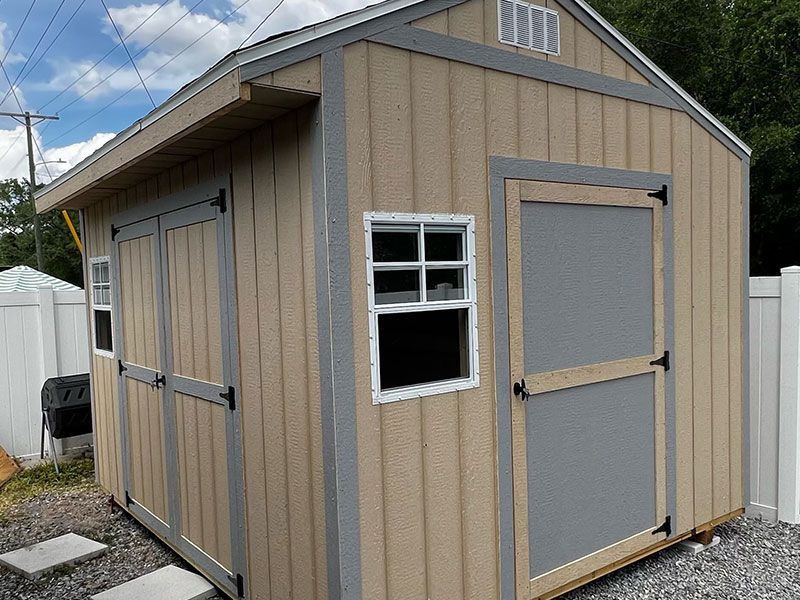 A tan and gray shed with a window on the side.