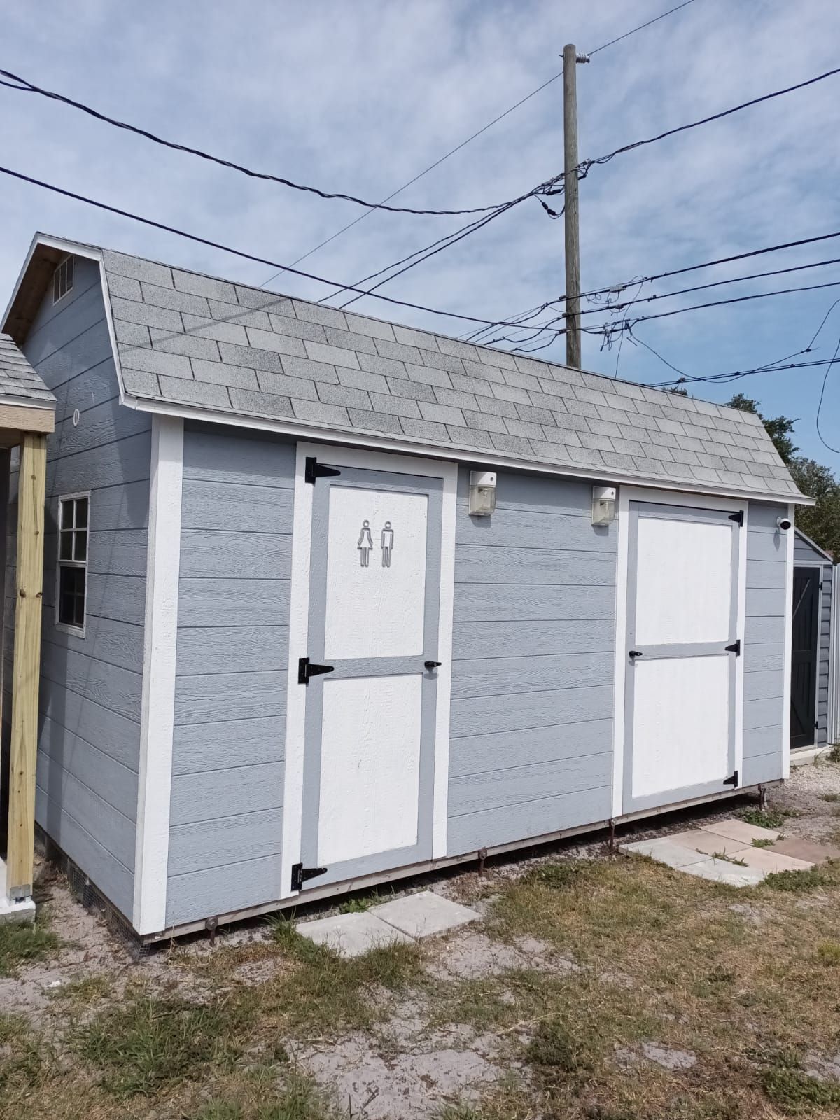 A gray and white shed with a gray roof is sitting in the grass