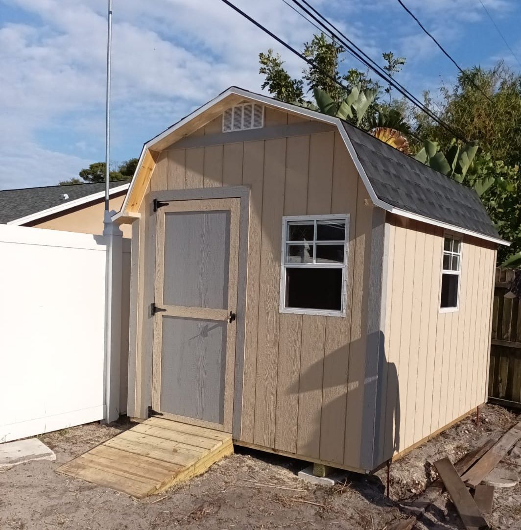 A small barn shaped shed with a ramp leading to it