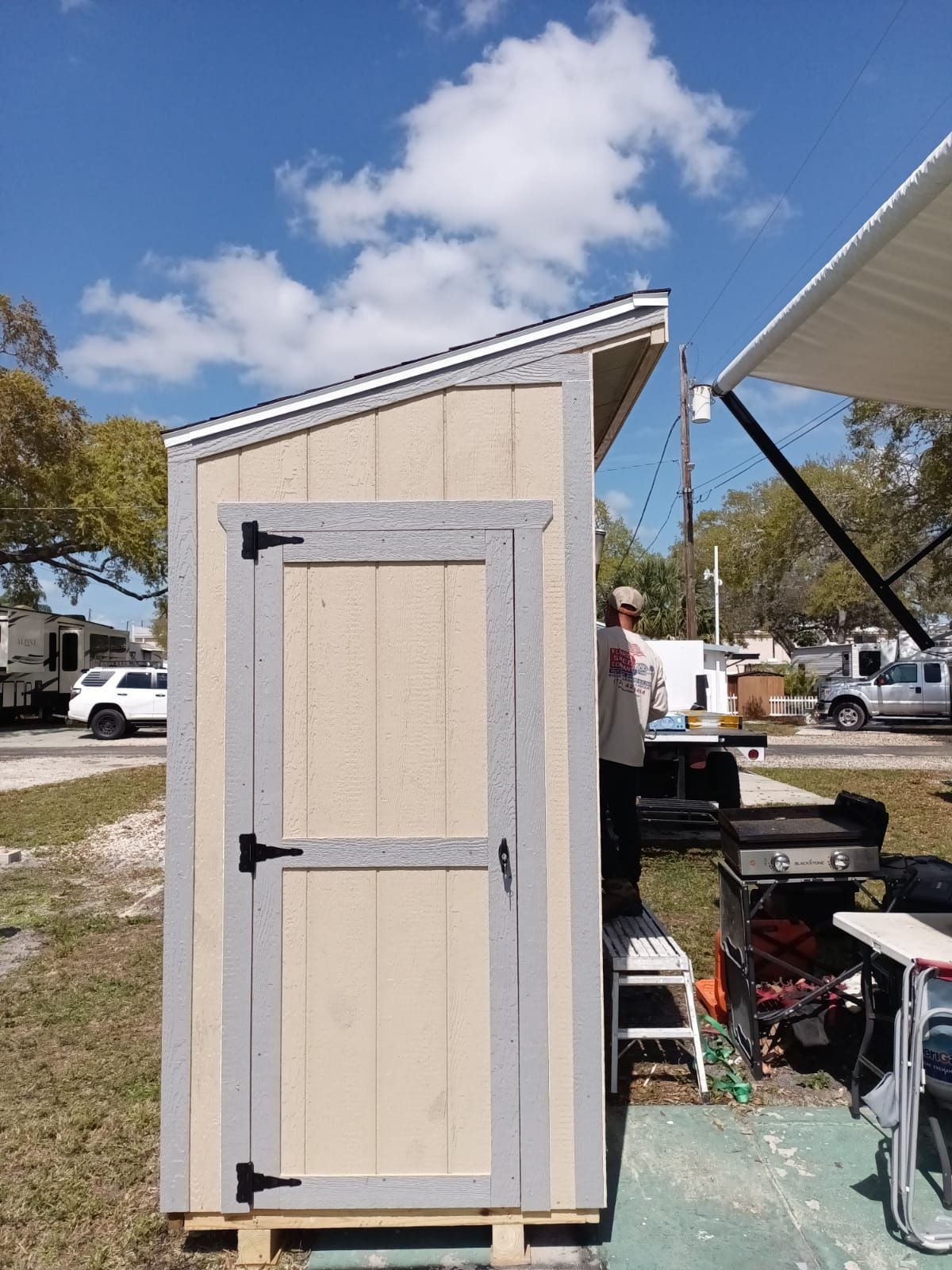 A man is standing in front of a small shed in a park