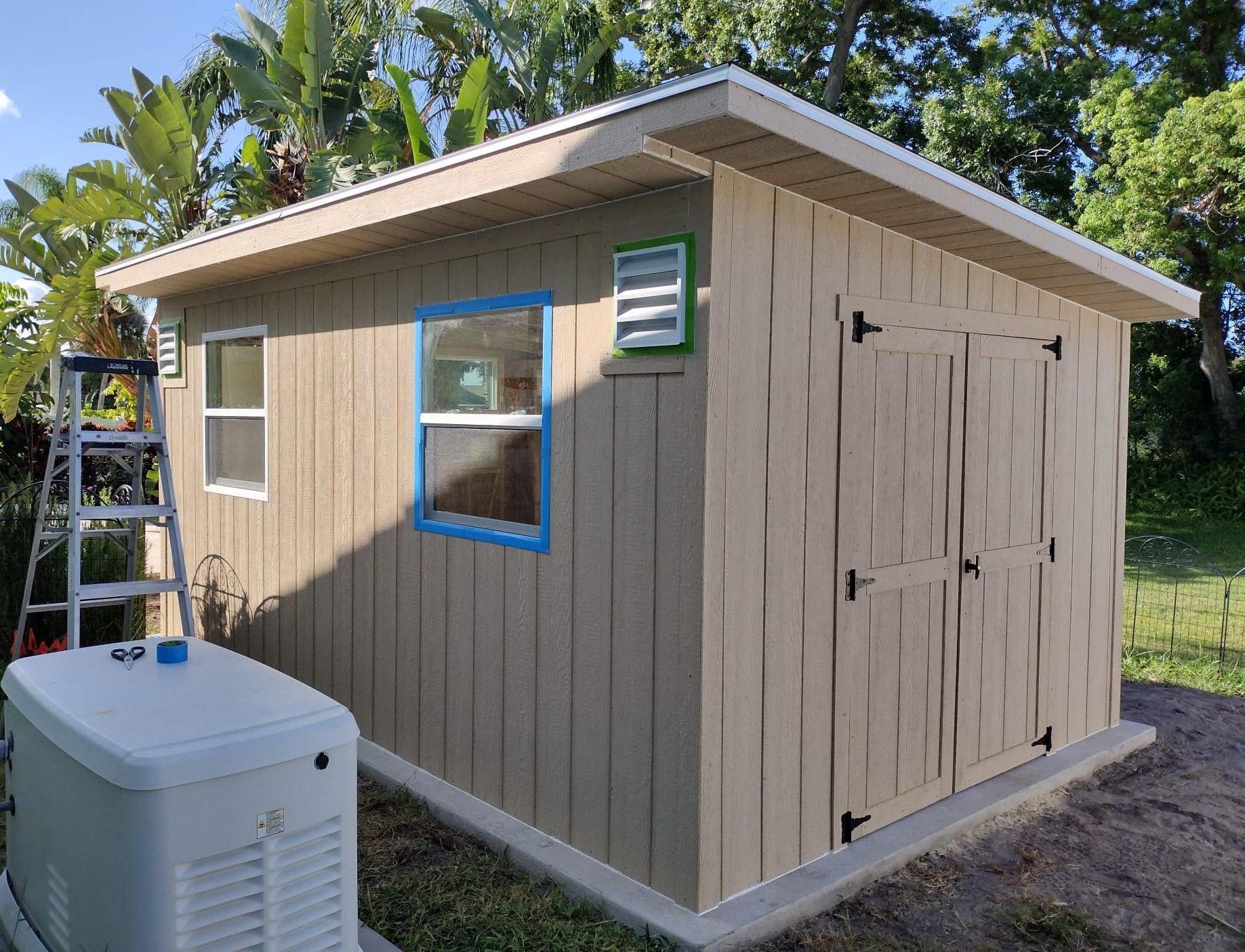 A small shed is being painted in the backyard