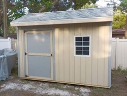 A small shed with a window and a white fence in the background