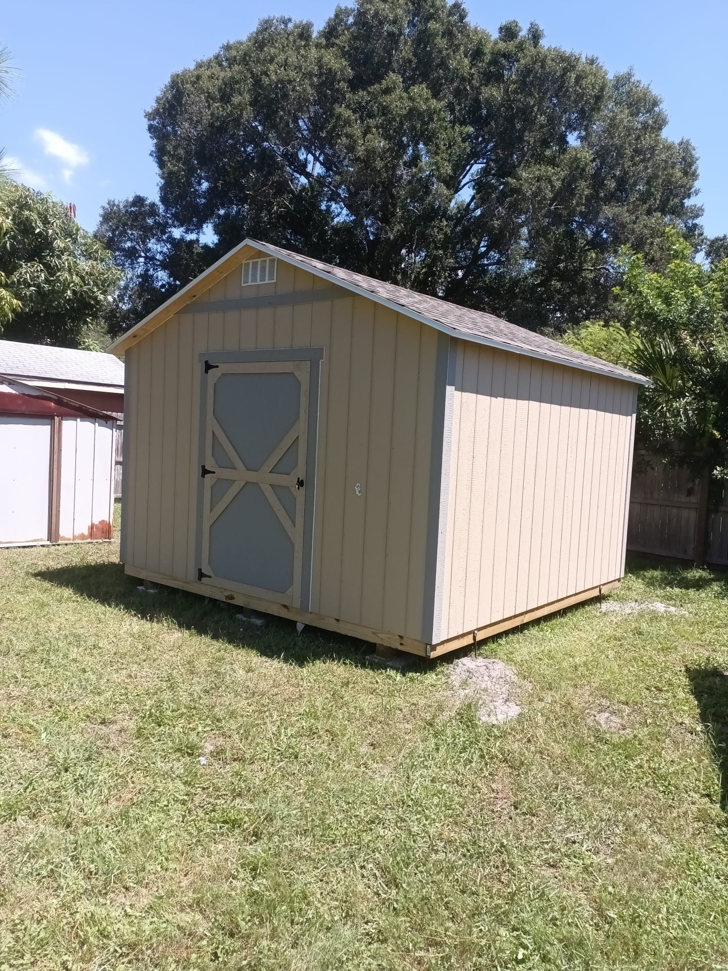 A small shed is sitting in the middle of a lush green field.