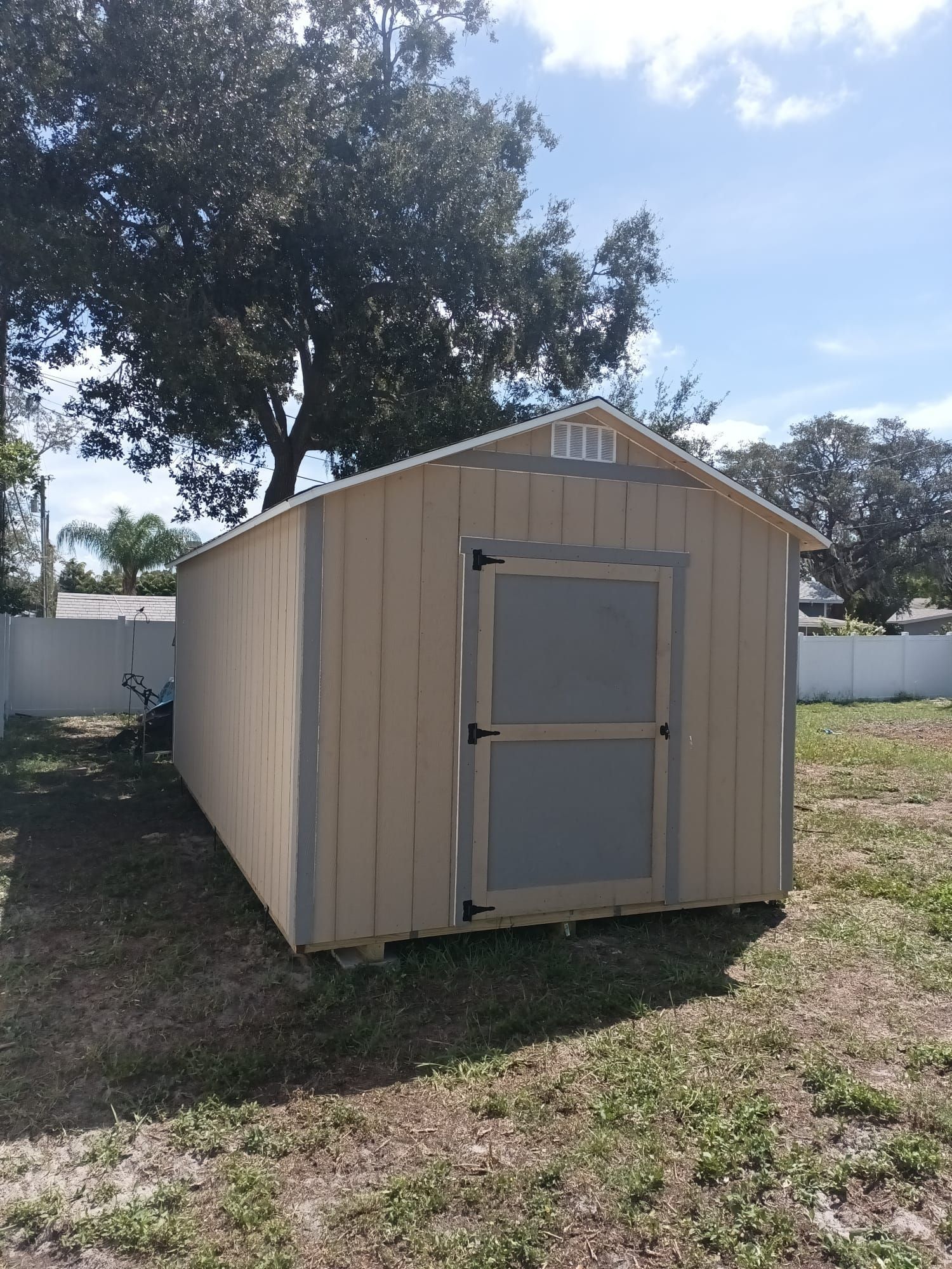 A small wooden shed is sitting in the middle of a grassy field.