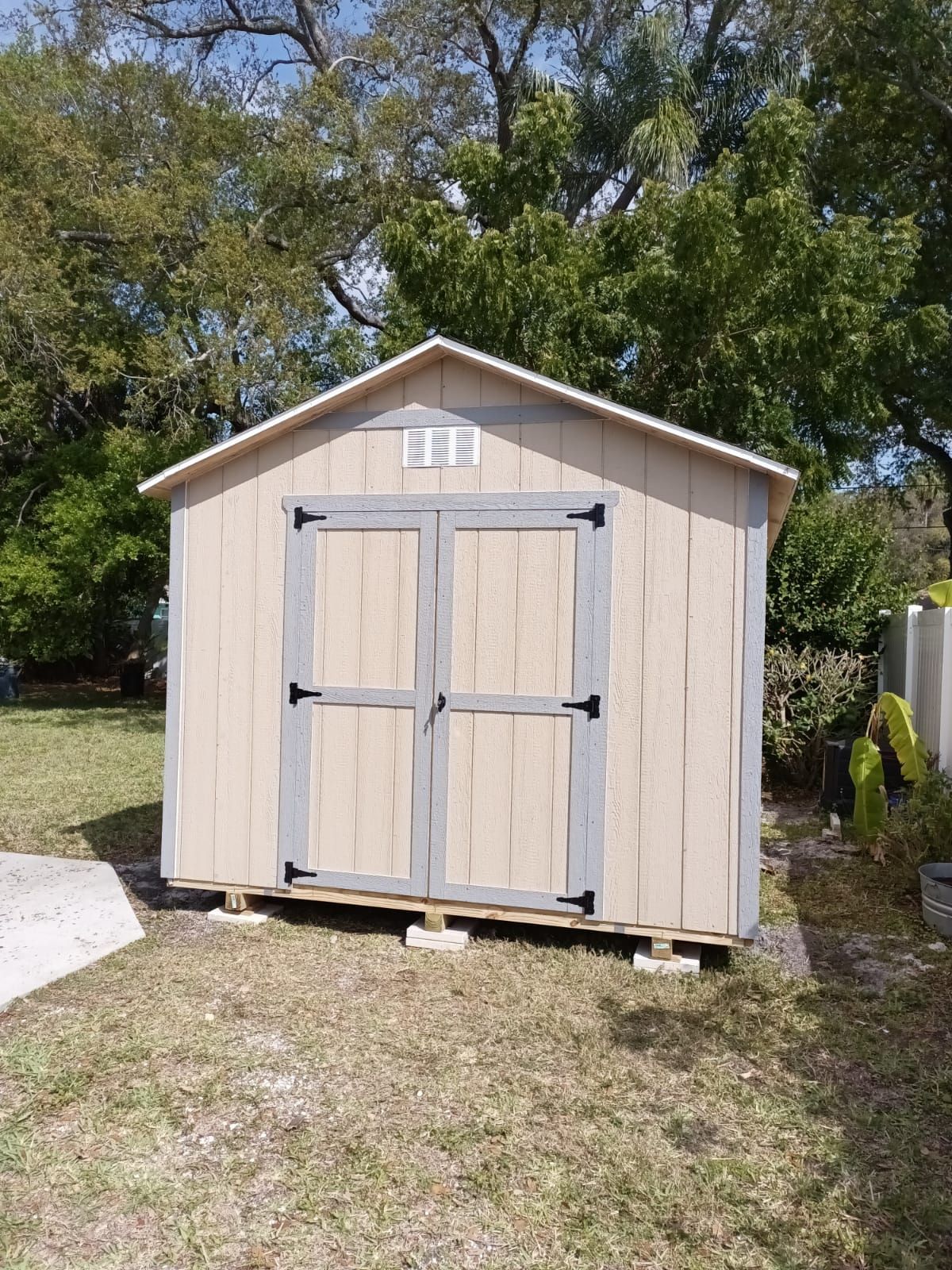 A small wooden shed is sitting in the middle of a grassy yard.