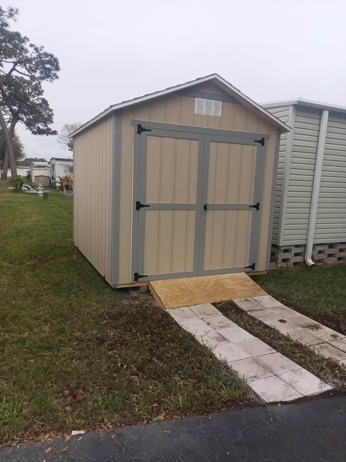 A small shed with a ramp leading to it is sitting in the grass.