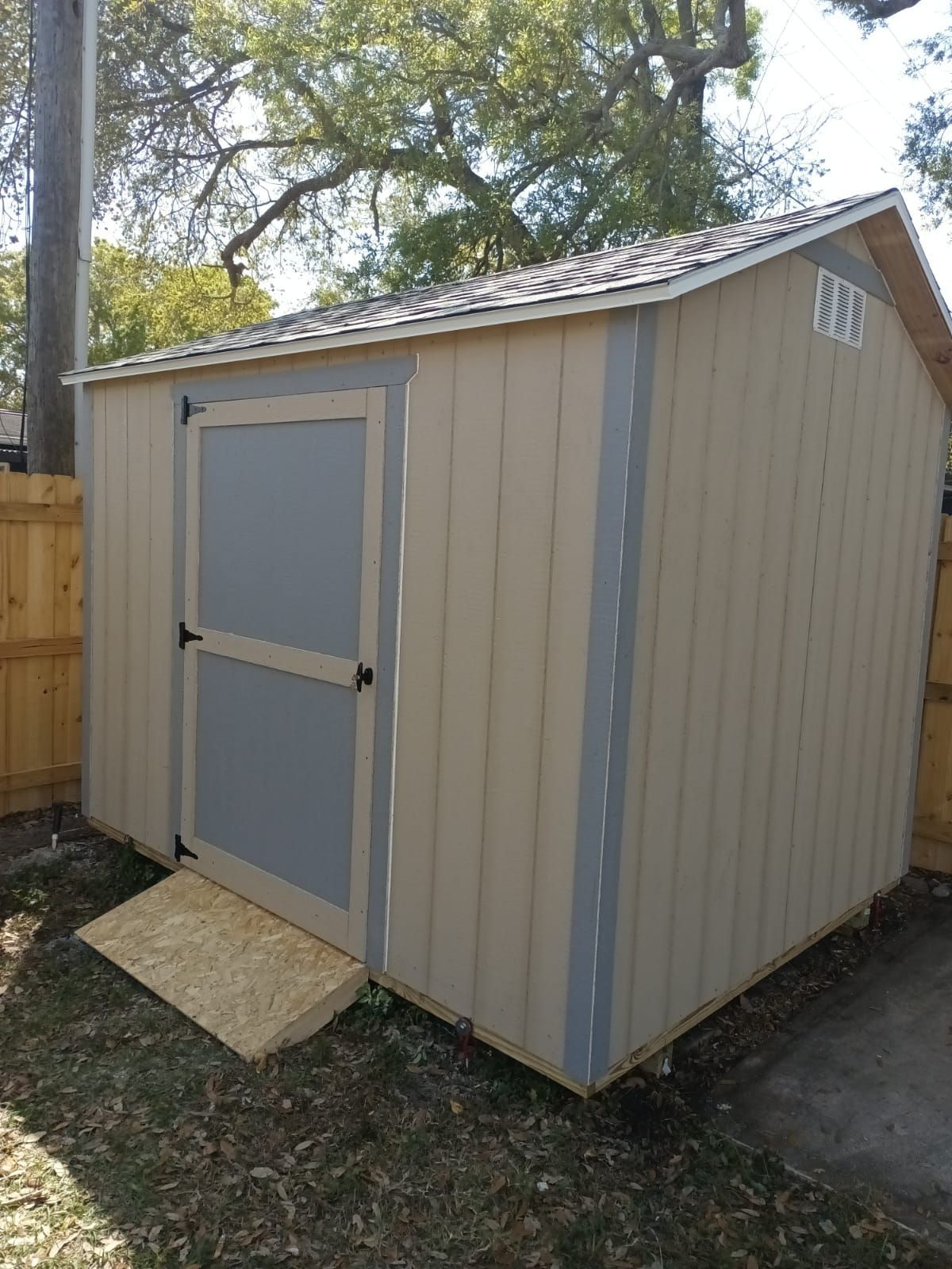 A small shed with a ramp in the backyard.