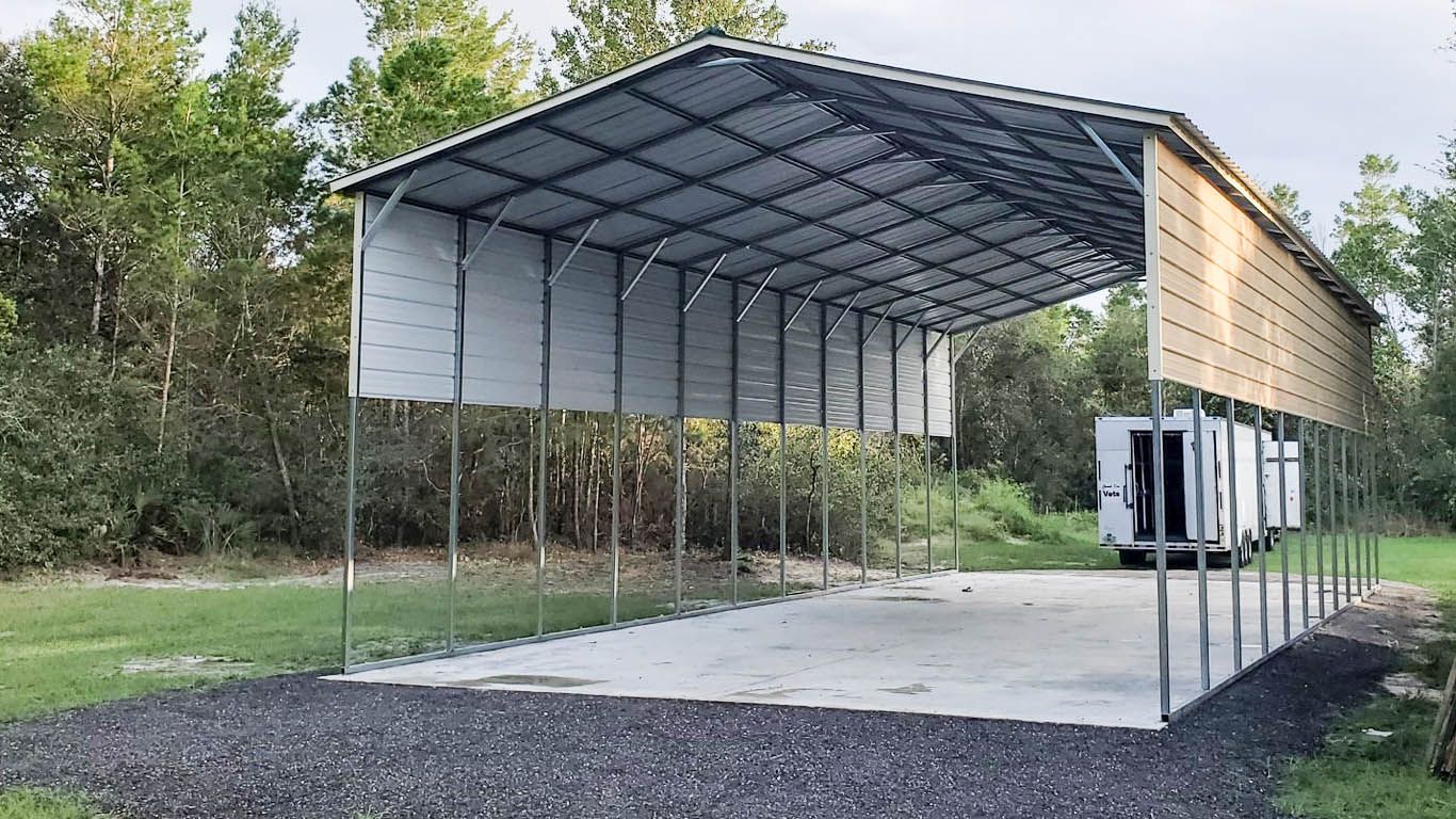 A large metal building is sitting on top of a gravel driveway.