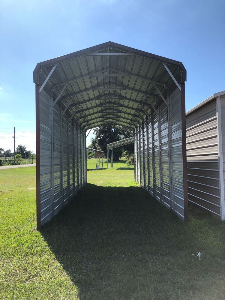 A carport is sitting in the middle of a grassy field.