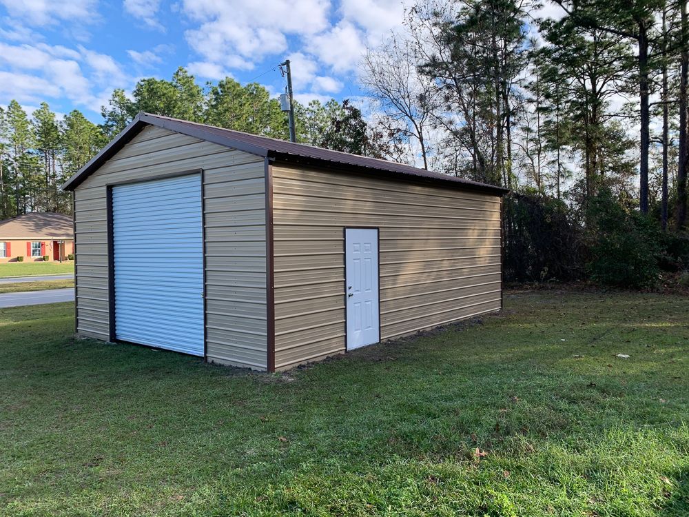 A metal garage with a white door is sitting in the middle of a grassy field.