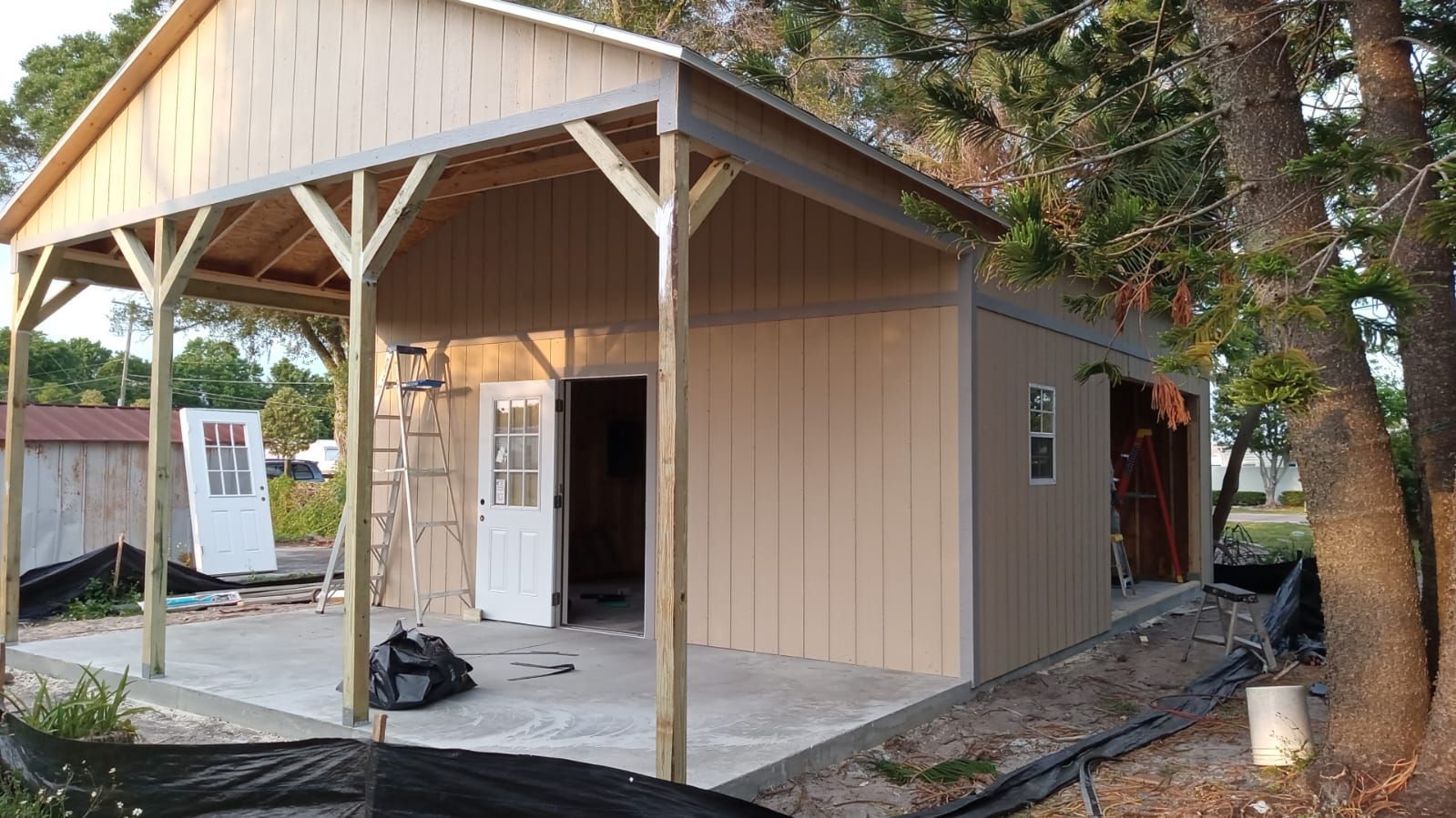 A shed with a porch and a ladder in front of it