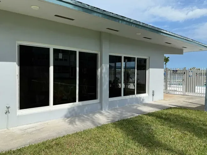 Light blue building with dark tinted windows, white trim, and a grassy area.