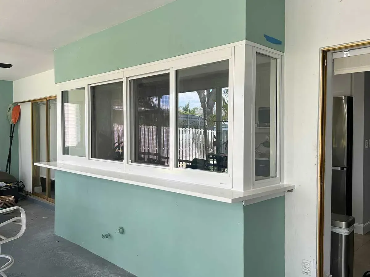 Bar-style window with white trim, mounted on a light blue wall. Interior and exterior seen through glass panes.