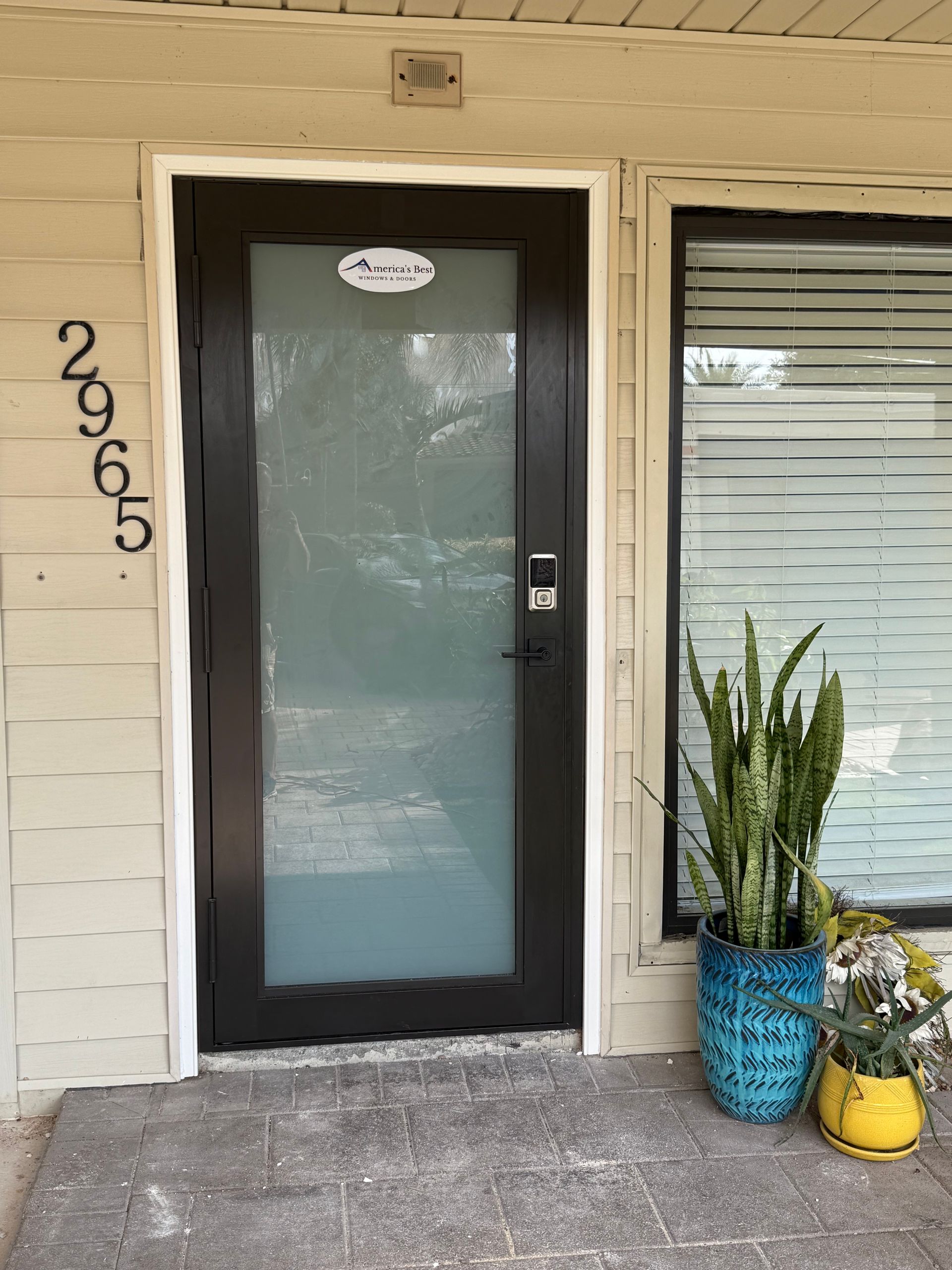 Black door with frosted glass, blue and yellow potted plants, building address 2965.