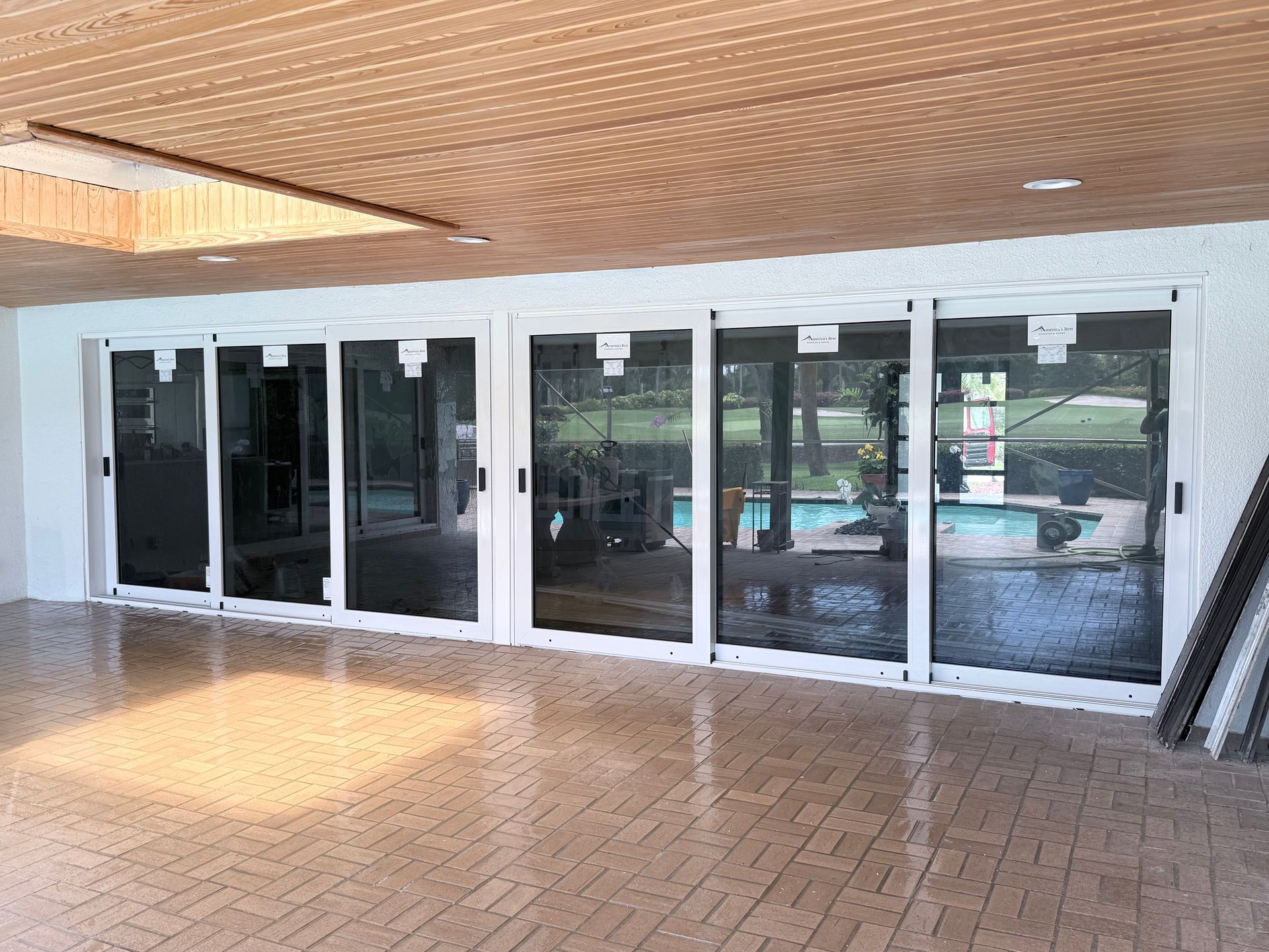 Glass storefront entrance with sliding doors and reflections in a tiled covered walkway