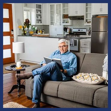 Mature guy sitting at the sofa reading a book