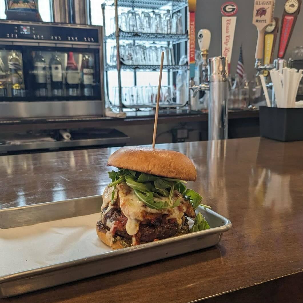 Gourmet burger on a tray at a bar counter with taps and drink fridge in the background