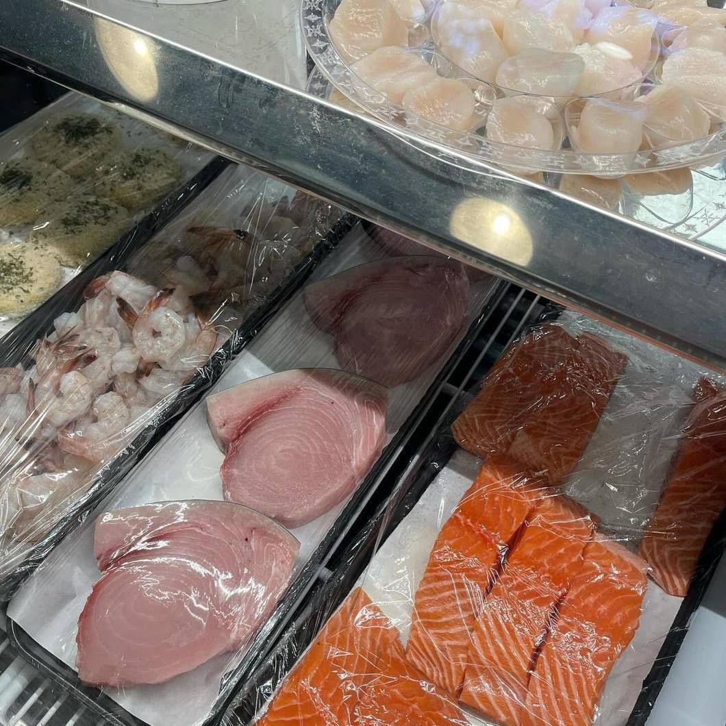 Seafood display case with raw salmon, tuna steaks, and shellfish on ice