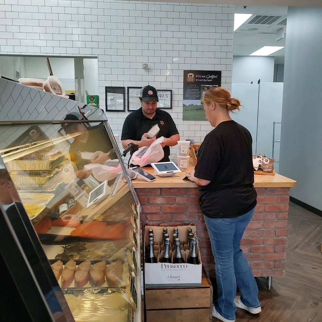 Two people at a bakery counter, with pastries displayed in a glass case.