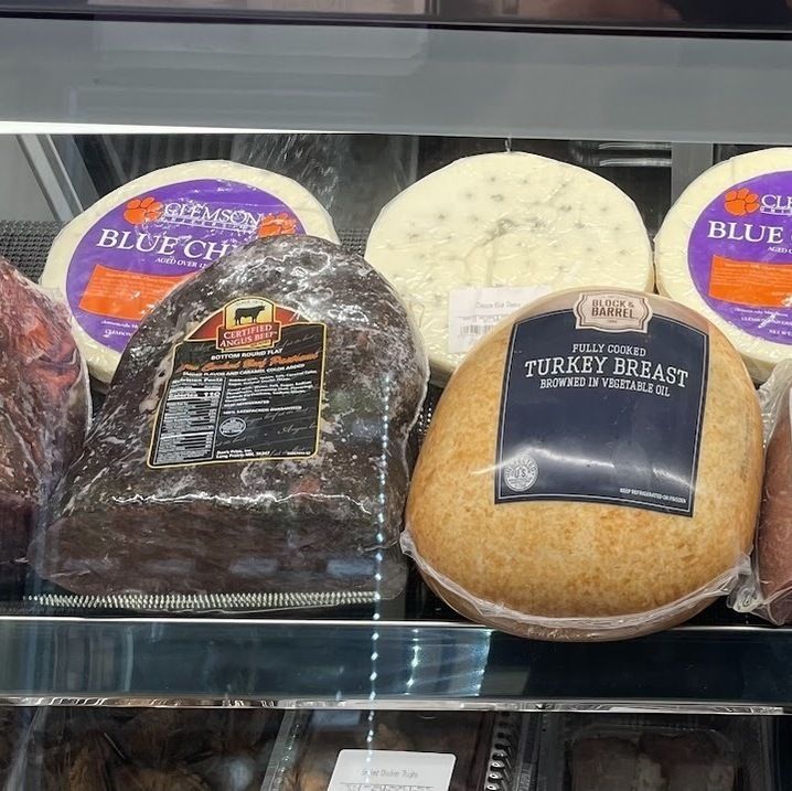 Deli case with wrapped sliced meats, including turkey breast and blue cheese, on a refrigerated shelf.
