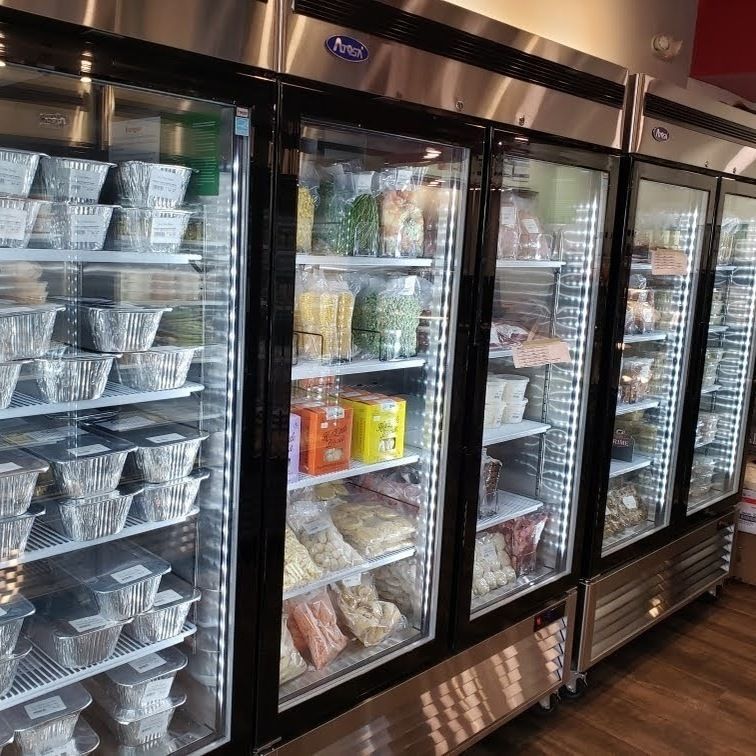 Refrigerated display cases filled with packaged food and drinks in a grocery or deli aisle