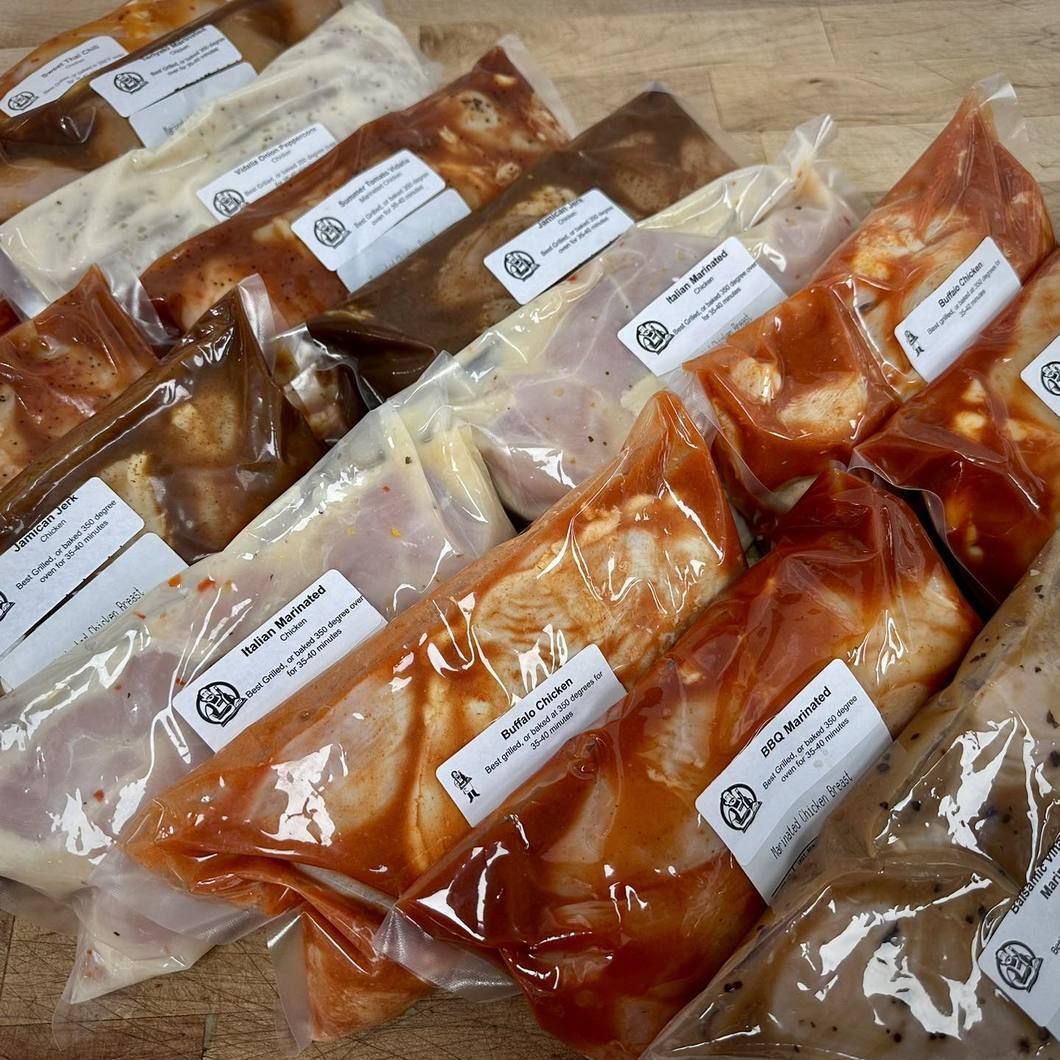 Assorted vacuum-sealed marinated meats in clear plastic bags on a table
