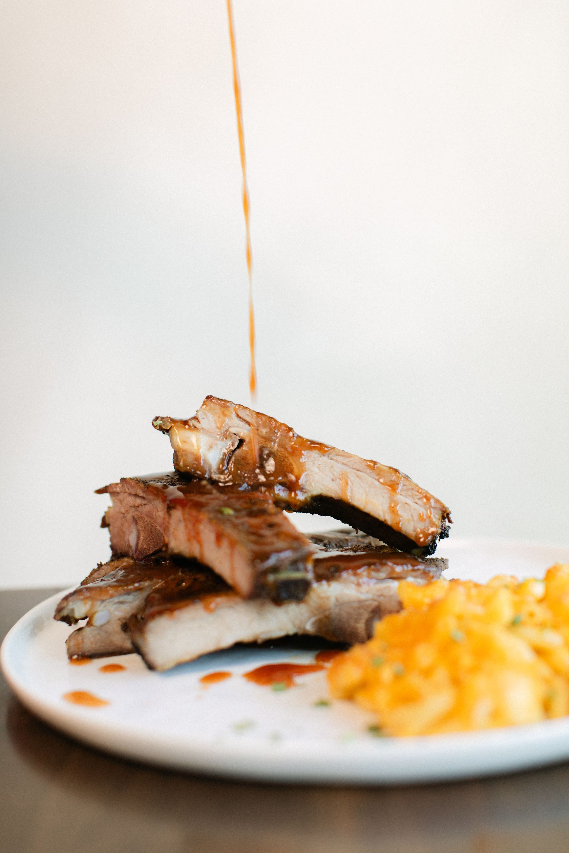 Plated grilled pork with sauce drizzle and mashed orange side on a white plate
