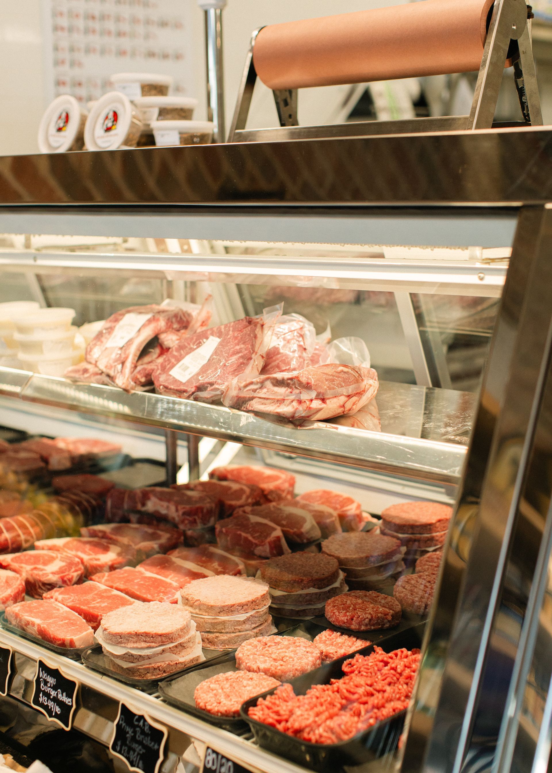 Deli meat display case with assorted red and pink cuts on trays under glass