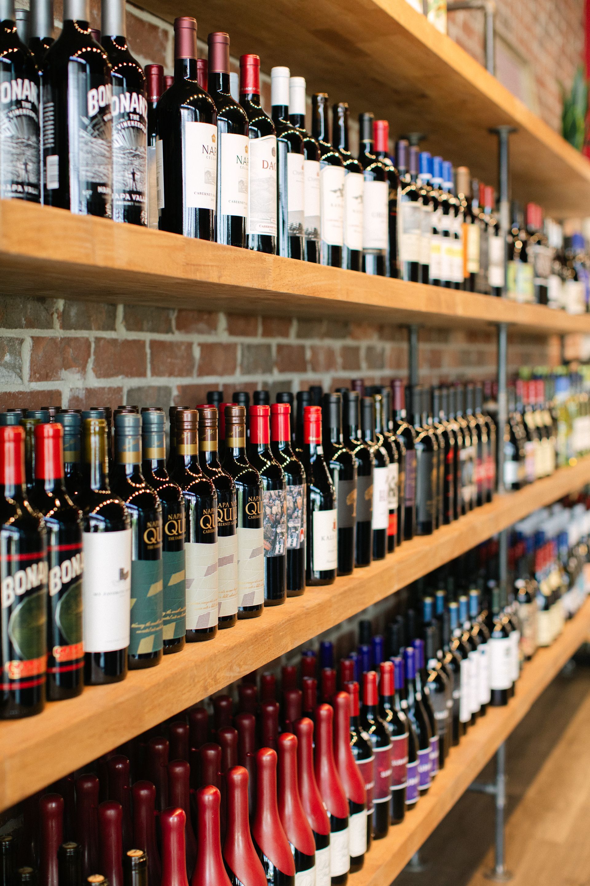 Rows of wine bottles displayed on wooden shelves in a shop