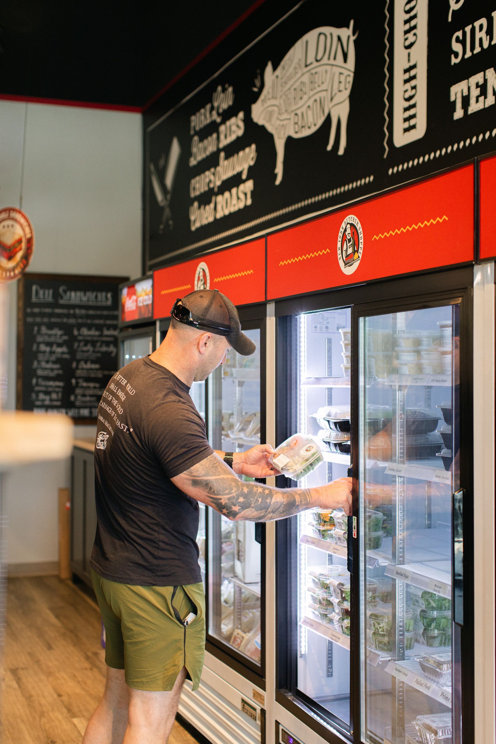 Man browsing drinks in a convenience store cooler under bright red signage