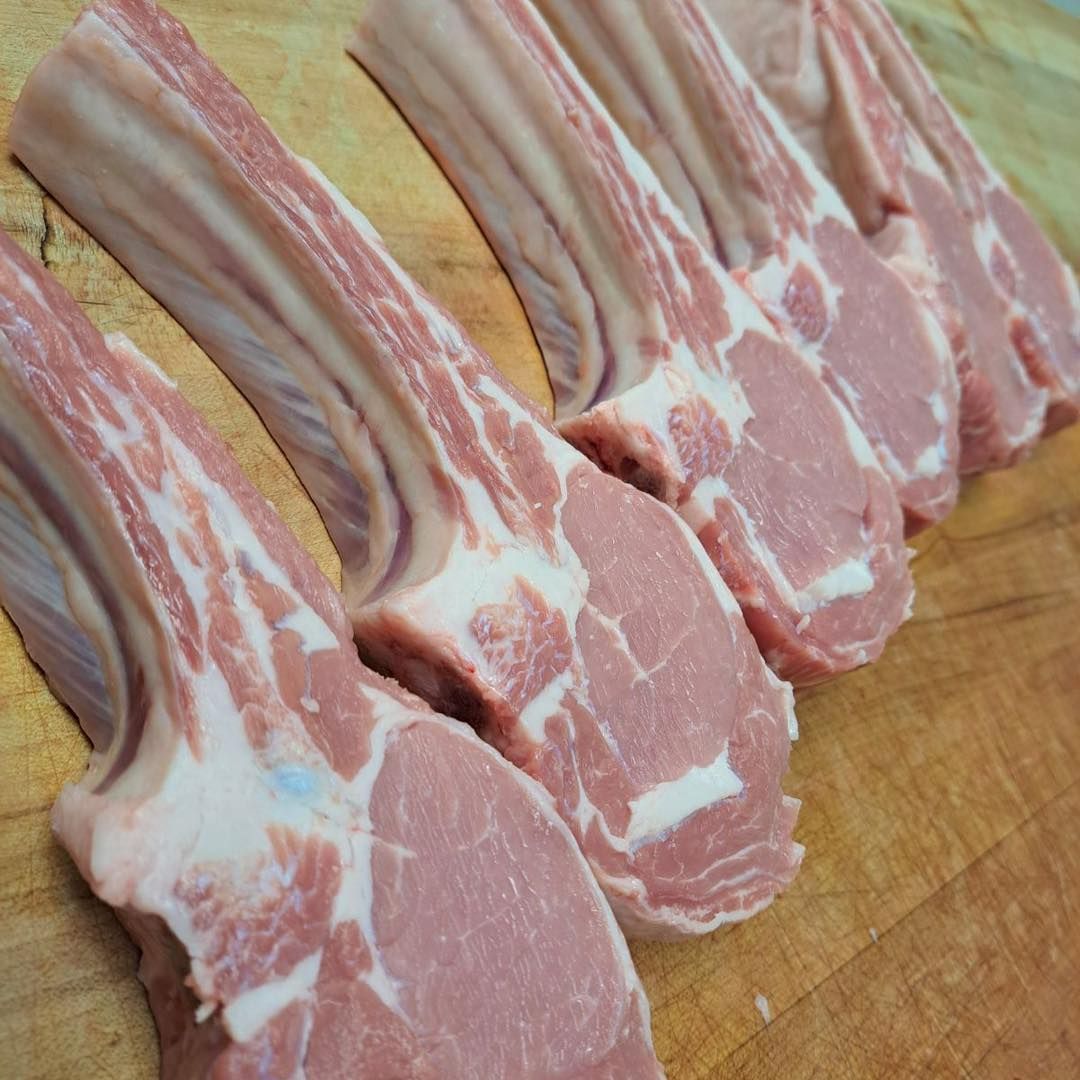 Raw lamb chops arranged on a wooden cutting board