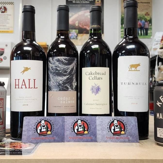 Four wine bottles on a store display, including Hall, Calabrese Cellars, and Tusk label bottles