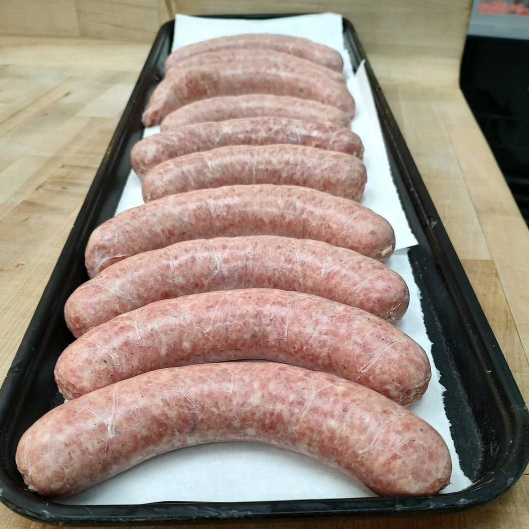 Raw sausages arranged in rows on a white-lined black tray