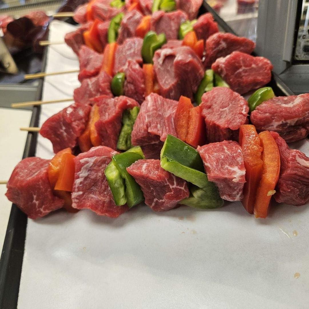 Beef and pepper skewers on a tray, ready for grilling.