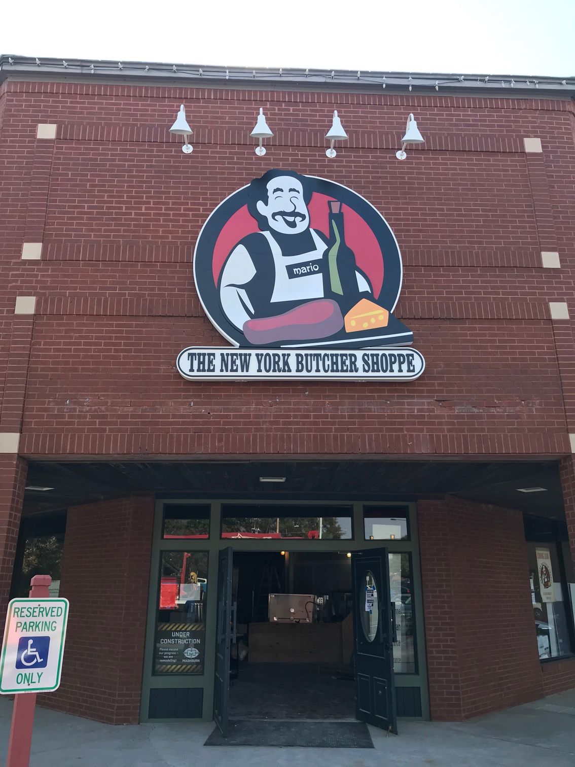 The New York Butcher Shoppe storefront with logo of a butcher, red brick, entrance.